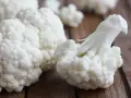 Białe różyczki kalafiora na drewnianym blacie. Niska wartość kalafior indeks glikemiczny czyni go idealnym wyborem dla zdrowej diety.