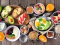 Szybkie śniadanie: jajka sadzone, tosty z awokado, bananem i truskawkami, owsianka, jogurt z owocami i sok pomarańczowy.
