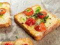 Pyszna, zdrowa kolacja na szybko: grzanki z roztopionym serem, pomidorkami koktajlowymi i szczypiorkiem.