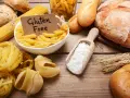 Miesiąc bez glutenu efekty: makarony, pieczywo i mąka na drewnianym stole.