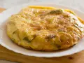 Złocista tortilla ziemniaczana z papryką na talerzu. Idealna jako pomysł na to, co zamiast chleba na śniadanie.