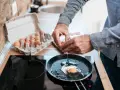 Mężczyzna wbija jajko na patelnię. Czy można jeść jajka przy chorej wątrobie? To pytanie nurtuje wiele osób.