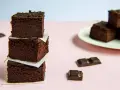 Ciemne, wilgotne brownie z fasoli i bananów, ułożone w wieżę, obok kawałków czekolady.