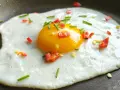 Jajko na patelni z posiekaną papryczką chili i szczypiorkiem. Idealne na szybkie śniadanie.