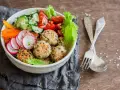 Kolorowa miska pełna zdrowia: kotleciki z komosy ryżowej, rzodkiewka, ogórek, pomidorki, papryka. Idealne przepisy na dietę przeciwzapalną.