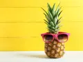 Ananas w okularach przeciwsłonecznych na żółtym tle. Czy wiesz, jaki ananas indeks glikemiczny ma dla diabetyków?