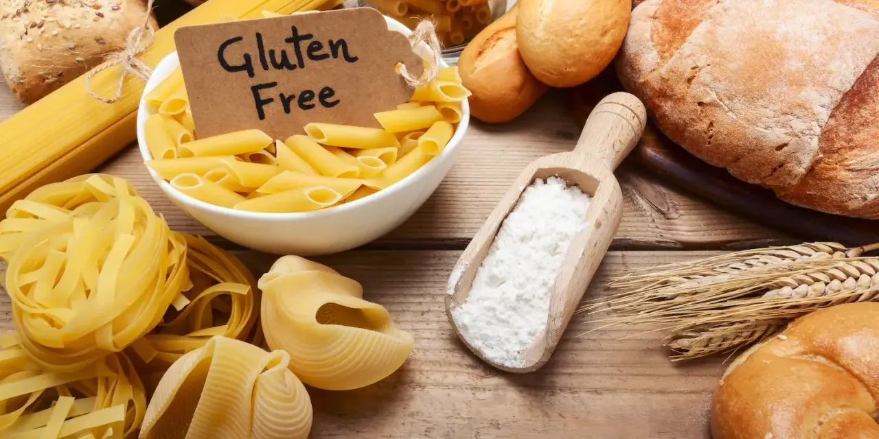Miesiąc bez glutenu efekty: makarony, pieczywo i mąka na drewnianym stole.