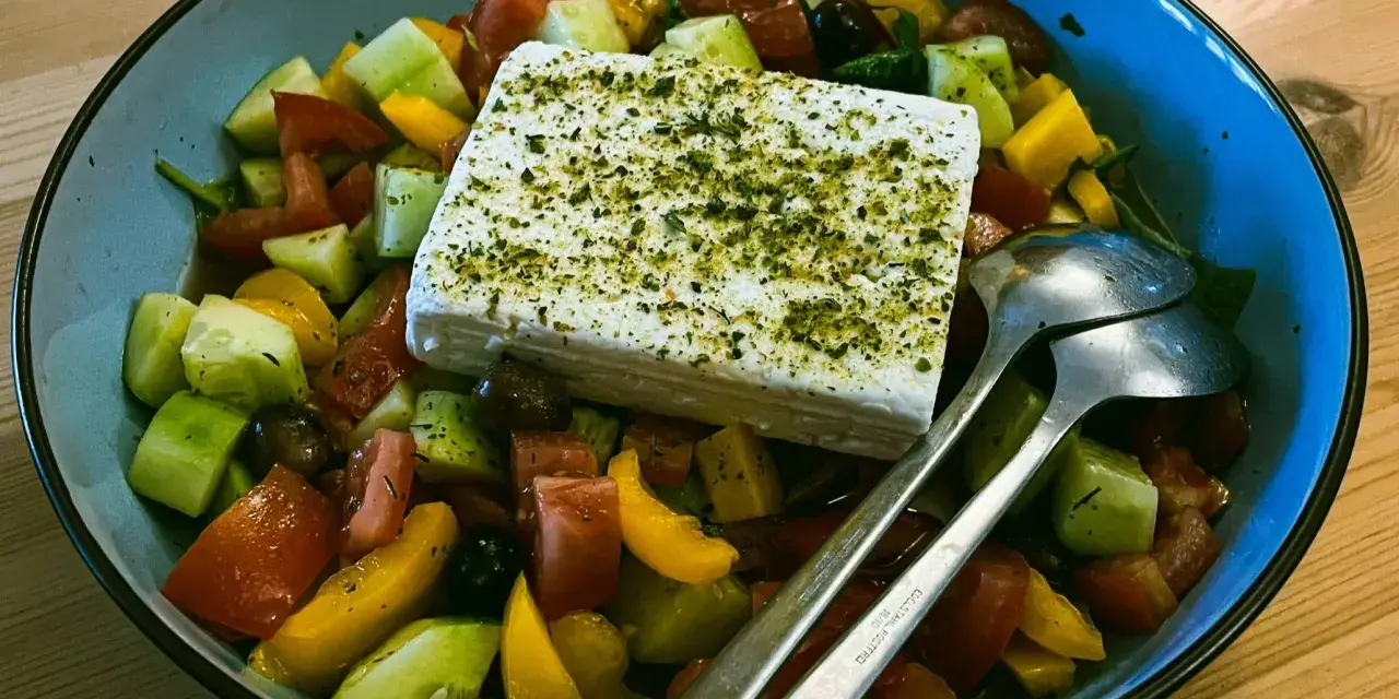 Sałatka grecka z kostką sera feta, pomidorami, ogórkiem i oliwkami. Czy ser feta jest zdrowy? Tak, to pyszny i zdrowy dodatek!