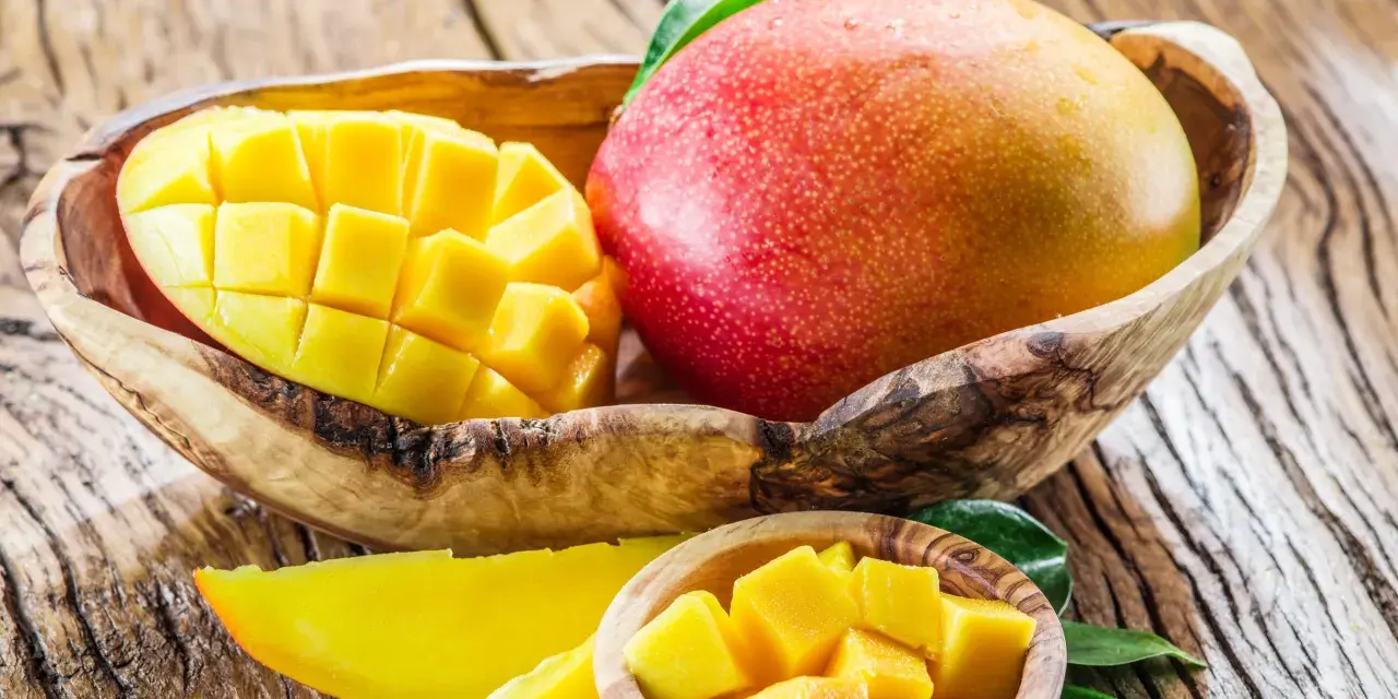 Dojrzałe mango w drewnianej misie, pokrojone w kostkę i plastry. To tropikalne owoce, które zachwycają smakiem i bogactwem witamin. Mango wartości odżywcze są imponujące.