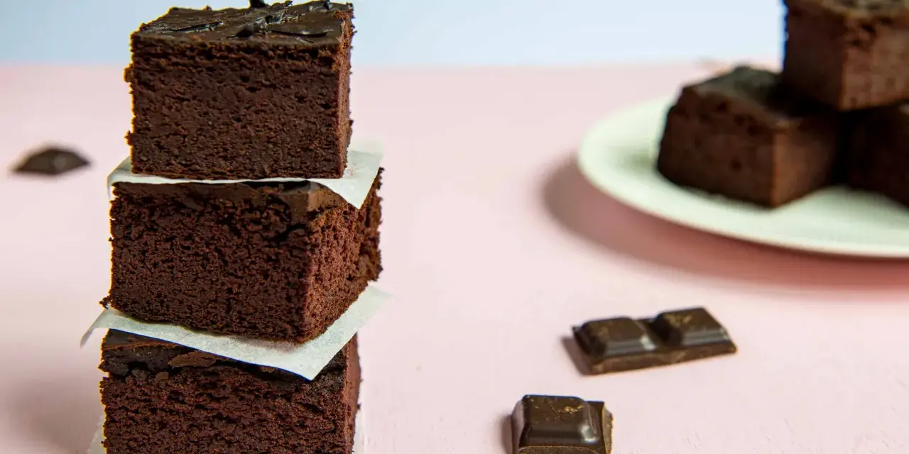Ciemne, wilgotne brownie z fasoli i bananów, ułożone w wieżę, obok kawałków czekolady.