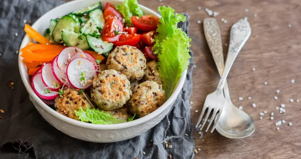 Kolorowa miska pełna zdrowia: kotleciki z komosy ryżowej, rzodkiewka, ogórek, pomidorki, papryka. Idealne przepisy na dietę przeciwzapalną.