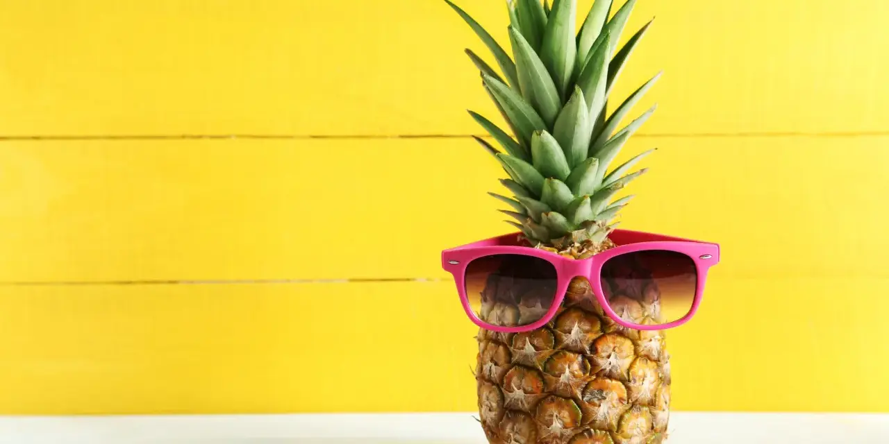 Ananas w okularach przeciwsłonecznych na żółtym tle. Czy wiesz, jaki ananas indeks glikemiczny ma dla diabetyków?