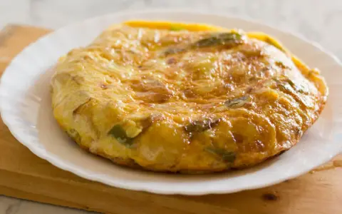 Złocista tortilla ziemniaczana z papryką na talerzu. Idealna jako pomysł na to, co zamiast chleba na śniadanie.