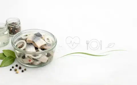 Słoik ze śledziami w zalewie, cebulą i pieprzem. Ikony serca, talerza z widelcem i nożem sugerują, czy śledzie są zdrowe.