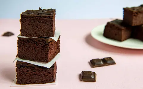 Ciemne, wilgotne brownie z fasoli i bananów, ułożone w wieżę, obok kawałków czekolady.
