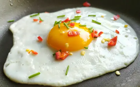 Jajko na patelni z posiekaną papryczką chili i szczypiorkiem. Idealne na szybkie śniadanie.