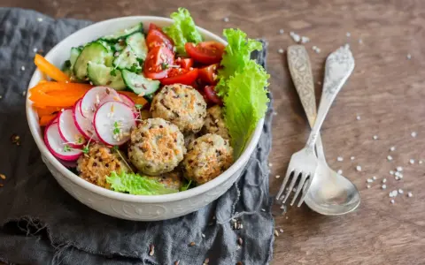 Kolorowa miska pełna zdrowia: kotleciki z komosy ryżowej, rzodkiewka, ogórek, pomidorki, papryka. Idealne przepisy na dietę przeciwzapalną.