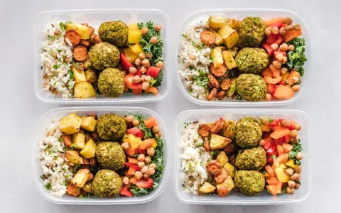 Cztery pojemniki z posiłkami: ryż, pieczone ziemniaki, marchewka, falafel, ciecierzyca i warzywa. Idealne na dieta 3000 kcal jadłospis tygodniowy.