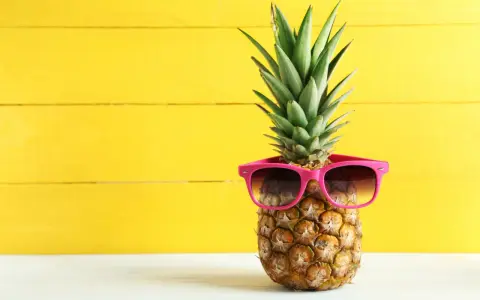 Ananas w okularach przeciwsłonecznych na żółtym tle. Czy wiesz, jaki ananas indeks glikemiczny ma dla diabetyków?