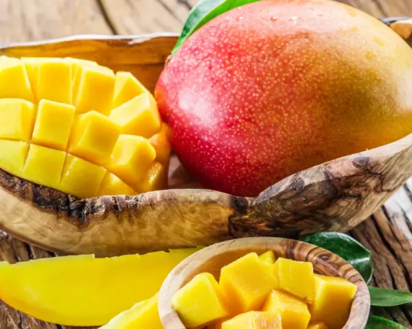 Dojrzałe mango w drewnianej misie, pokrojone w kostkę i plastry. To tropikalne owoce, które zachwycają smakiem i bogactwem witamin. Mango wartości odżywcze są imponujące.
