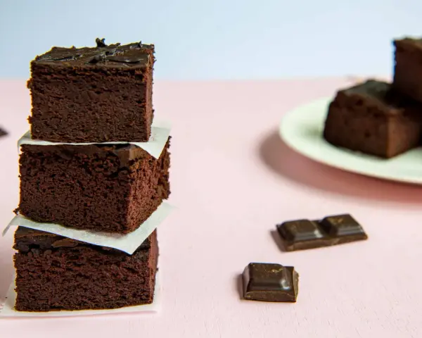 Ciemne, wilgotne brownie z fasoli i bananów, ułożone w wieżę, obok kawałków czekolady.