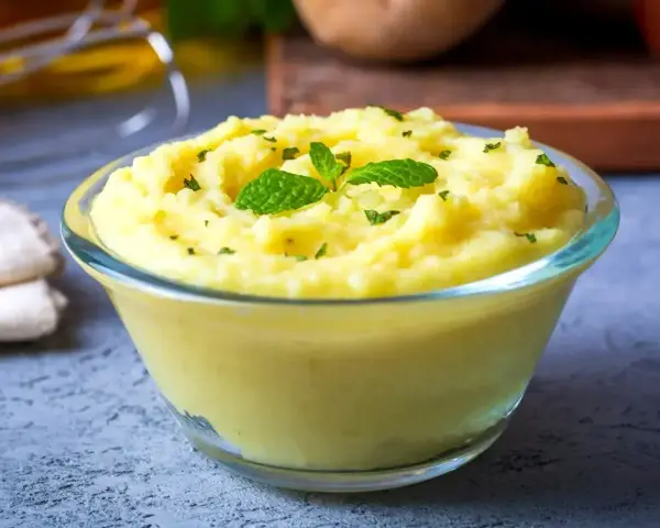 Gładkie, kremowe puree ziemniaczane, idealne jako zmiksowane jedzenie dla chorego przepisy. Udekorowane listkami mięty i posypane ziołami.