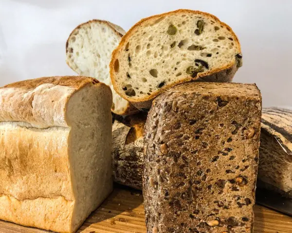 Różne rodzaje pieczywa, w tym bochenek z ziarnami, który może być odpowiedzią na pytanie: czy chleb razowy jest zdrowy?
