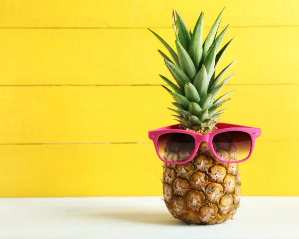 Ananas w okularach przeciwsłonecznych na żółtym tle. Czy wiesz, jaki ananas indeks glikemiczny ma dla diabetyków?