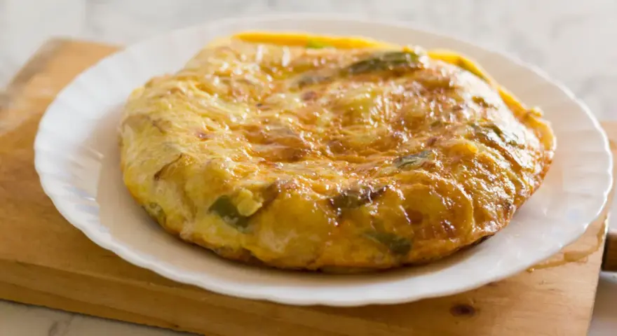 Złocista tortilla ziemniaczana z papryką na talerzu. Idealna jako pomysł na to, co zamiast chleba na śniadanie.