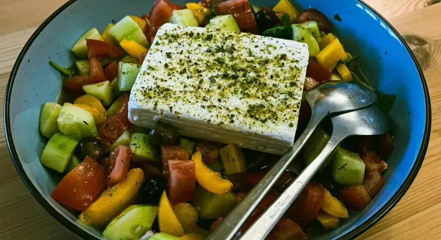 Sałatka grecka z kostką sera feta, pomidorami, ogórkiem i oliwkami. Czy ser feta jest zdrowy? Tak, to pyszny i zdrowy dodatek!